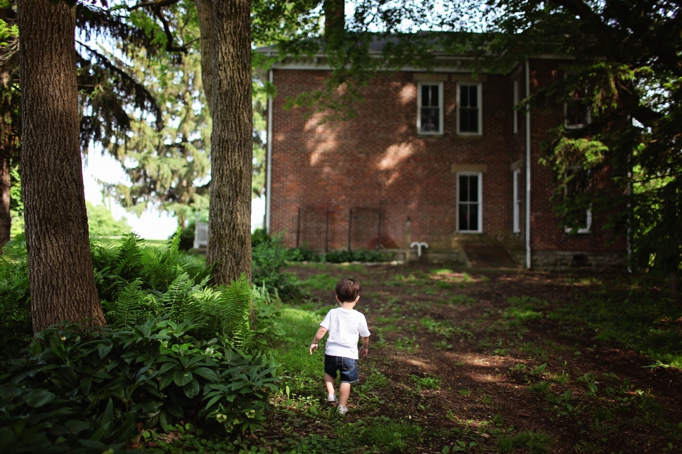 boy in white t-shirt walking towards brown concrete house preview